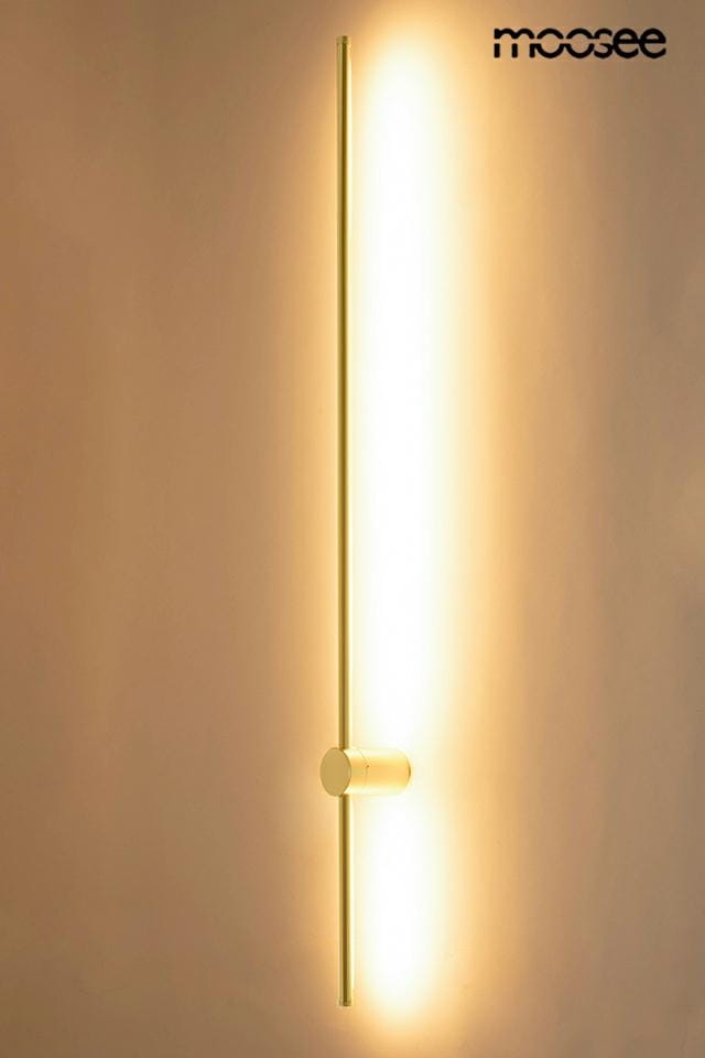 Kinkiet Ombre 120 w kolorze złotym, z jedną diodą LED o mocy 14W. Produkt ma prostą, pionową formę z okrągłą podstawą. Emituje ciepłe światło, z delikatnym podświetleniem wzdłuż lampy, zamontowany na jasnym tle.