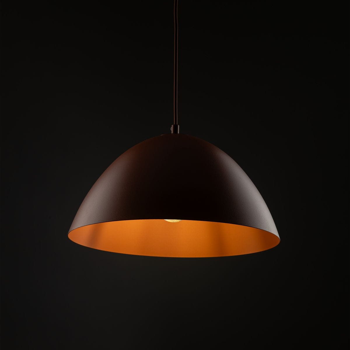 Lampa wisząca Faro D34 w kolorze ceglastym, o zaokrąglonym kształcie, z jedną oprawą E27. Widoczny matowy klosz zewnętrzny oraz pomarańczowe wnętrze, zawieszona na cienkim przewodzie, na tle ciemnego tła.