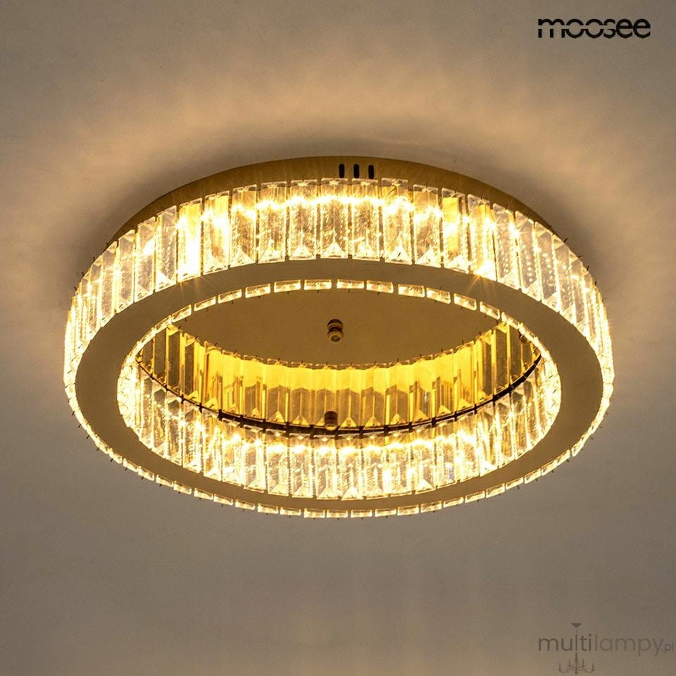 Lampa sufitowa Borra z złotą obręczą, wyposażona w diodę LED 25W. Ma okrągły kształt, z transparentnym kloszem, który odbija światło. Ujęcie z dołu, ukazujące detale konstrukcji oraz efekt świetlny. Idealna do nowoczesnych wnętrz.