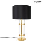 Lampa stołowa Moxy z podstawą w złotym kolorze i czarnym abażurem. Konstrukcja z przezroczystych elementów, stojąca z kablem zasilającym na dole. Abażur o klasycznym kształcie, podkreślający elegancki design.