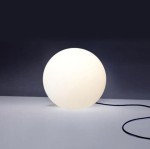 Lampa ogrodowa Cumulus S w kształcie białej kuli, wykonana z matowego materiału. Produkt leży na stole, z widocznym kablem zasilającym. Idealna do użytku na zewnątrz, dodaje nowoczesnego akcentu każdemu otoczeniu.