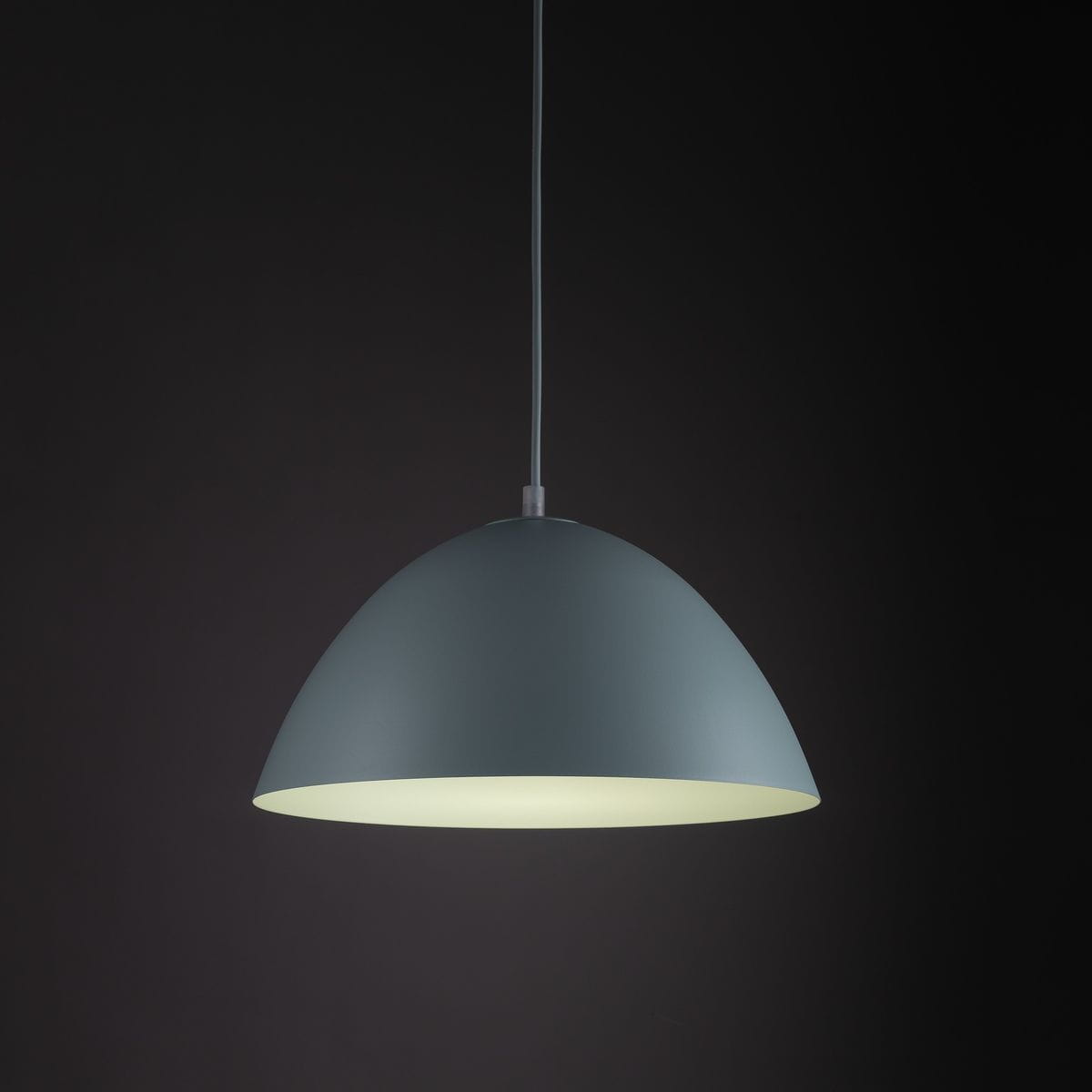 Lampa wisząca Faro D34 w miętowym kolorze z abażurem w kształcie półkuli, zawieszona na cienkim kablu. Wewnątrz biała powierzchnia, która rozprasza światło. Tło ciemne, podkreślające kolor lampy.