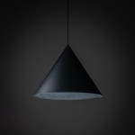 Lampa wisząca Cono D50 w kształcie stożka, czarna, z możliwością użycia żarówki E27. Zawieszona na cienkim przewodzie, z matową powierzchnią i otwartą dolną częścią, która umożliwia rozproszenie światła. Tło ciemne.