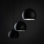 Lampa wisząca Zoe w kolorze czarnym z trzema okrągłymi kloszami, zawieszona na cienkich linkach. Klosze mają matową powierzchnię i otwartą dolną część, co umożliwia wydobywanie światła. Ujęcie z przodu, na ciemnym tle.