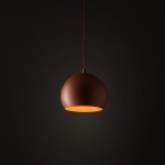 Ceglasta lampa wisząca Zoe D17, o okrągłym kształcie, zawieszona na cienkim przewodzie. Wnętrze klosza w kolorze żółtym, matowe wykończenie na zewnątrz. Prosta forma, odpowiednia do nowoczesnych wnętrz. Tło ciemne, minimalistyczne.