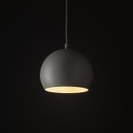 Lampa wisząca Zoe D17 w beżowym kolorze, o okrągłym kształcie, zawieszona na białym przewodzie. Emituje ciepłe światło przez otwór na dole. Ujęcie z przodu, na jednolitym, ciemnym tle.