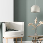 Beżowa lampa wisząca Zoe D17 z jednym gniazdem E27, o zaokrąglonym kształcie, zawieszona nad eleganckim fotelem w białym kolorze, w otoczeniu stonowanej zielonej ściany i dekoracyjnych kwiatów w wazonie.