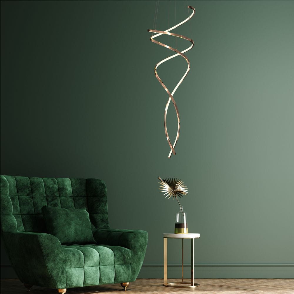 Lampa wisząca Coco w kolorze złotym, z pilotem, z dwoma źródłami światła LED o mocy 68W. Ma spiralny kształt i jest zawieszona nad zielonym, welurowym fotelem w nowoczesnym wnętrzu. W tle ciemnozielona ściana.