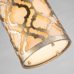 Lampa wisząca Arabella w kolorze starego złota, z metalowym kloszem o ażurowym wzorze, eksponującym ciepłe światło. Widok z bliska na detale klosza oraz zamocowanie, w kształcie cylindrycznym.