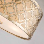 Lampa wisząca Arabella w kolorze starego złota z trzema oprawkami E27. Ozdobna klosz z ażurowym wzorem, subtelnie przepuszczający światło, ujęta pod kątem, eksponująca detale i teksturę.