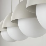 Beżowa lampa wisząca Bono z czterema kloszami, z białymi, matowymi kulami. Klosze mają półokrągły kształt i teksturowaną powierzchnię. Ujęcie z bliska, ukazujące detale konstrukcji i materiałów. Idealna do nowoczesnych wnętrz.