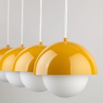 Lampa wisząca Bono z czterema kloszami w kolorze żółtym i białym. Klosze mają kształt półkulisty, z gładką, błyszczącą powierzchnią, zawieszone na białych linkach. Produkt idealny do nowoczesnych wnętrz.