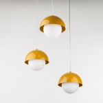 Lampa wisząca Bono z trzema źródłami światła G9, z kloszami w kształcie półkul, w kolorze białym z żółtymi, błyszczącymi osłonami. Produkt zawieszony na białych kablach, prezentowany na jasnym tle.