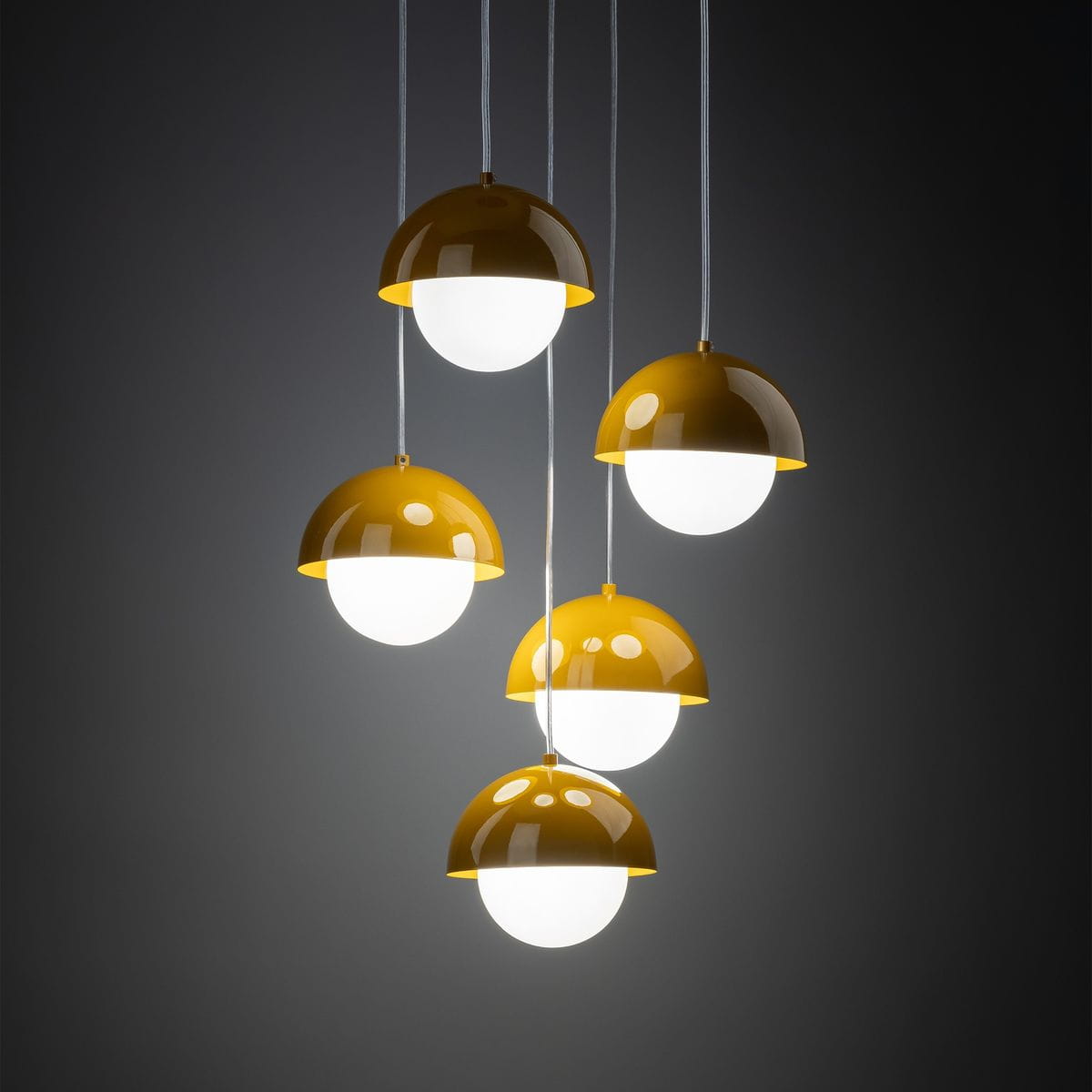 Lampa wisząca Bono z pięcioma kloszami G9 w kolorze ochra. Klosze mają półkulisty kształt, zewnętrzna część jest błyszcząca, a wewnętrzna biała, zawieszone na białych przewodach. Ujęcie frontalne na tle ciemnym.