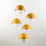Lampa wisząca Bono z pięcioma źródłami światła G9, w kolorze żółtym i białym. Posiada półkuliste klosze z błyszczącego metalu oraz matowego szkła. Zawieszona na białych przewodach, prezentuje nowoczesny design.