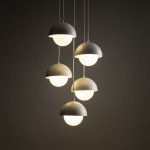 Beżowa lampa wisząca Bono z pięcioma kloszami w kształcie półkul, zawieszona na cienkich przewodach. Klosze mają białe, szklane wnętrza, emitujące miękkie światło. Lampa wisi w pionie, na ciemnym tle.