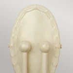 Kinkiet Minster 2xE14 w kolorze kości słoniowej. Owalna, gładka obudowa z dekoracyjnym wzorem i dwoma cylindrycznymi uchwytami. Stojący, minimalistyczny design, idealny do nowoczesnych wnętrz.