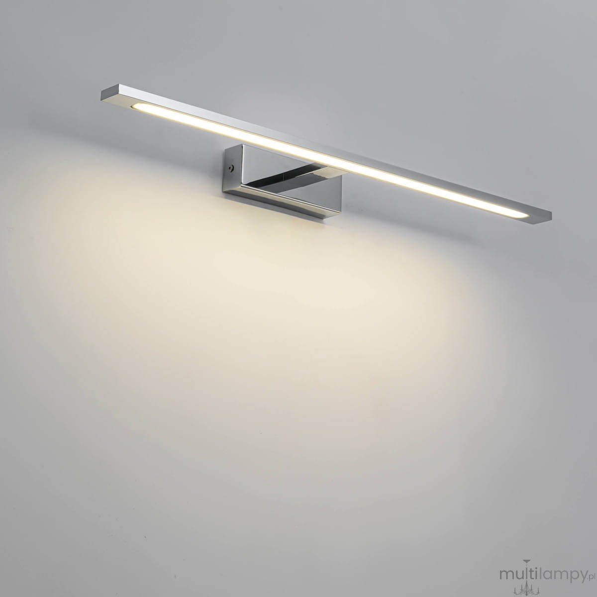 Kinkiet LED Isla IP44 w kolorze chromu, prostokątny, z wbudowanym źródłem światła, zamontowany na ścianie. Posiada minimalistyczny design i emituje jasne, ciepłe światło, idealny do oświetlenia wnętrz.