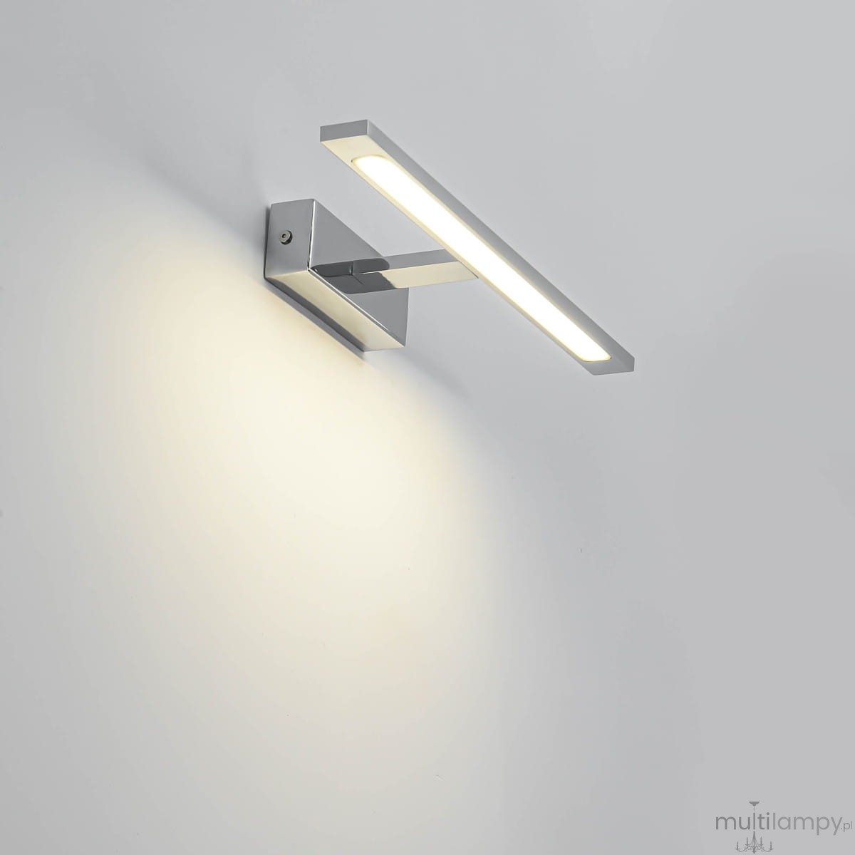 Kinkiet LED Isla IP44 w kolorze chromowanym, o prostokątnym kształcie, montowany na ścianie. Emituje ciepłe światło, z widocznym chromowanym uchwytem. Produkt w pozycji stojącej, na jasnym tle.