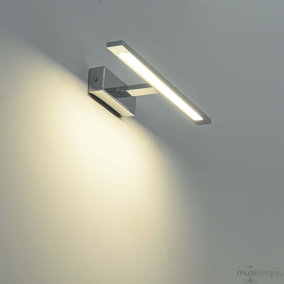 Kinkiet LED Isla IP44 w kolorze chromu, w kształcie prostokąta, montowany na ścianie. Emituje ciepłe światło, z widoczną obudową o minimalistycznym designie. Zainstalowany pod kątem, idealny do nowoczesnych wnętrz.