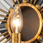 Kinkiet Sun King w odcieniu starego złota, z pojedynczym uchwytem na żarówkę E14. Okrągła podstawa z wykończeniem w złotym kolorze, otoczona promieniami z przezroczystych kryształków. W centralnej części widoczna świecąca żarówka.