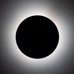 Brązowy kinkiet Luna z miejscem na cztery żarówki G9, o okrągłej formie. Zainstalowany na ścianie, emituje subtelne, rozproszone światło wokół krawędzi, podkreślając nowoczesny design. Tło jasne, minimalistyczne.