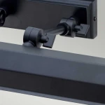 Kinkiet Chawton M w kolorze czarnym, z podwójnym ramieniem, przeznaczony do żarówek E14. Zbliżenie na mechanizm mocowania i regulacji, z prostym, minimalistycznym designem, idealny do oświetlenia obrazów lub dekoracji ściennych.