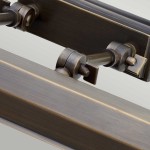 Kinkiet obrazowy Chawton L w antycznym brązie, z widocznymi detalami mocowania i regulacji. Ujęcie z bliska, ukazujące metaliczne wykończenie oraz mechanizm montażowy. Idealny do oświetlenia obrazów.