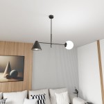 Lampa wisząca Hermes w kolorze czarnym, z jednym kloszem w formie stożka oraz jednym okrągłym. Ujęcie z góry, ukazujące montaż na suficie w nowoczesnym wnętrzu z drewnianą ścianą i jasną sofą. Wymiary i detale kształtów kloszy są widoczne.