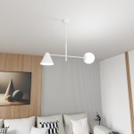 Lampa wisząca Hermes w kolorze białym z jednym kloszem w kształcie stożka i jednym okrągłym, zawieszona na białym przewodzie. Produkt umieszczony w nowoczesnym wnętrzu z drewnianą ścianą i jasną sofą.