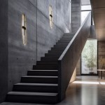 Kinkiet Flash w kolorze czarnym, 2xLED/24W, zamontowany na ścianie przy schodach. Prosta, nowoczesna forma z pionowymi elementami świetlnymi, emitującymi ciepłe światło. Tło w odcieniach szarości, minimalistyczne wnętrze z dużymi oknami.