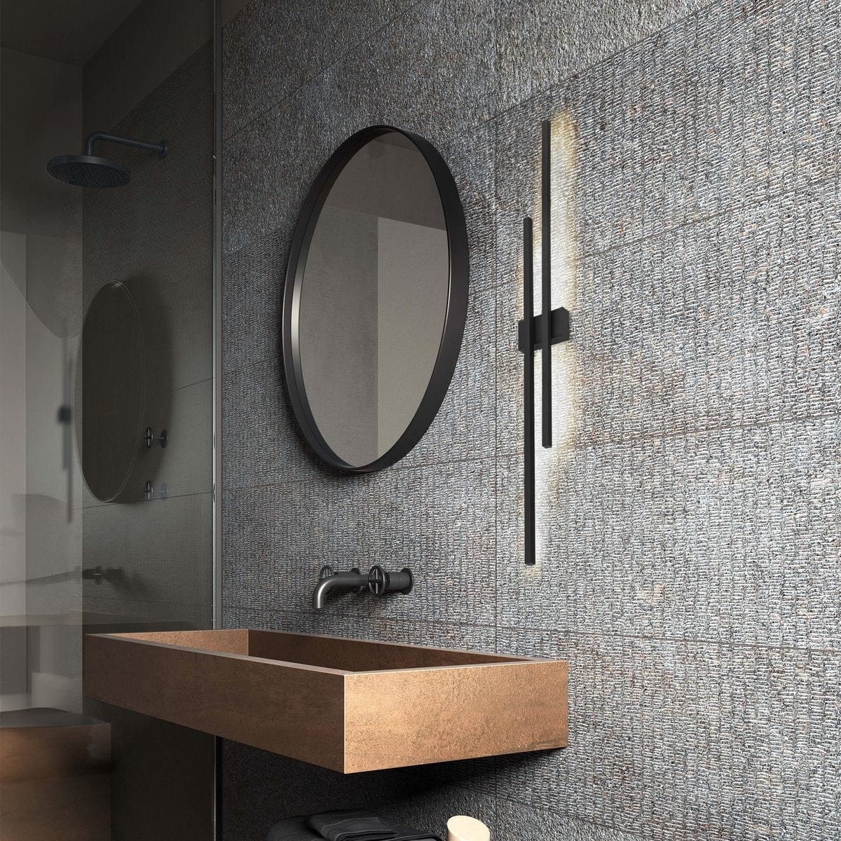 Kinkiet Flash w kolorze czarnym, z dwoma źródłami LED o mocy 24W, zamontowany na ścianie w łazience, obok okrągłego lustra. Oświetlenie emitujące łagodne światło, w nowoczesnym, minimalistycznym stylu.