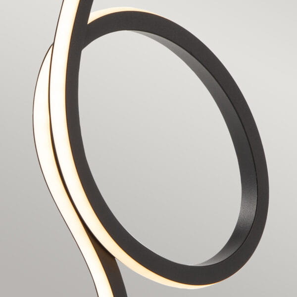 Czarna lampka stołowa Flamingo z jedną diodą LED 6W, o nowoczesnym, zakrzywionym kształcie. Widoczne elementy to matowa, czarna obudowa oraz podświetlana krawędź, tworząca efektowne oświetlenie. Ujęcie z boku, na jasnym tle.