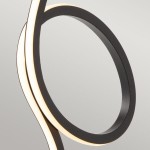 Czarna lampka stołowa Flamingo z jedną diodą LED 6W, o nowoczesnym, zakrzywionym kształcie. Widoczne elementy to matowa, czarna obudowa oraz podświetlana krawędź, tworząca efektowne oświetlenie. Ujęcie z boku, na jasnym tle.