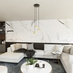 Lampa wisząca Elit 3xGX53 w kolorze czarnym i złotym, zawieszona na trzech cienkich przewodach. Wisi na tle marmurowej ściany, nad jasnoszarym narożnikiem. W zestawie widoczna jest elegancka aranżacja wnętrza, w tym stół z książkami i roślinnością.