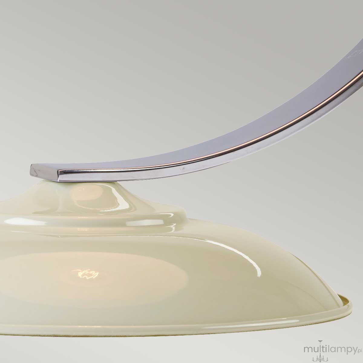 Lampka stołowa Franklin w kolorze kremowym z metalowym, lekko zakrzywionym uchwytem. Widoczna ceramiczna podstawa oraz oprawa na żarówkę E27. Ujęcie z boku, ukazujące detale kształtu i materiału. Tło jednolite, szare.