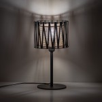 Lampka stołowa Harmony w kolorze czarnym i brązowym z metalowym kloszem w geometrycznym wzorze. Stoi na okrągłej podstawie, z widoczną żarówką E27. Tło jednolite, podkreślające design lampy.