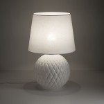 Lampa stołowa Santana z białym, tekstylnym kloszem i kulistą podstawą z fakturowanej ceramiki. Ujęcie z boku, ukazujące detale wzoru na podstawie oraz delikatne światło wydobywające się z klosza.