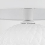 Lampa stołowa Santana 1xE27 w kolorze białym, z ceramicznym kloszem o teksturowanej powierzchni w kształcie diamentów. Ujęcie z bliska, pokazujące mocowanie klosza do białej podstawy. Tło jasne, proste, co podkreśla detal produktu.