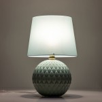 Lampa stołowa Santana w kolorze zielonym/miętowym z okrągłą, teksturowaną podstawą oraz prostym, lekko przezroczystym kloszem. Ujęcie z boku, stojąca na płaskiej powierzchni, z widocznym kablem.