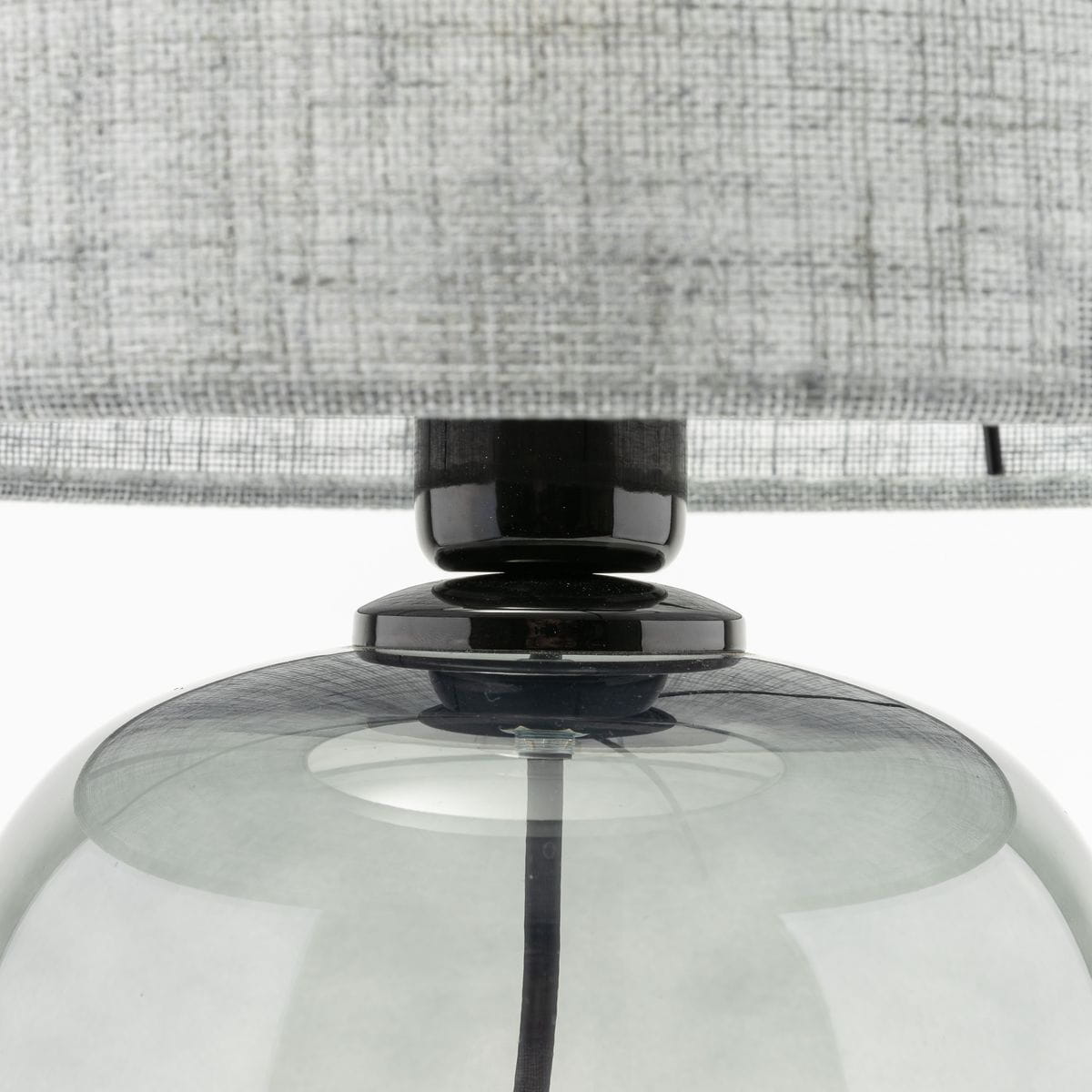 Lampa stołowa Melody z grafitowym podstawą i szarym abażurem, zbliżenie na szklaną kulę i czarny element łączący. Abażur wykonany z tekstylnego materiału, widoczne detale struktury.