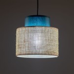 Lampa wisząca Duo D20 z kloszem z juty w naturalnym odcieniu, z niebieską górną częścią. Posiada miejsce na żarówkę E27. Zawieszona pod kątem, w tle ciemne, neutralne kolory.
