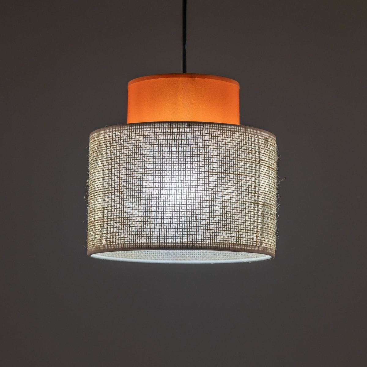 Lampa wisząca Duo D20 z pomarańczowym kloszem z tworzywa i jutowym abażurem, w kształcie cylindrycznym. Ujęcie z dołu, pokazujące detale materiałów i struktury, zawieszona na czarnym przewodzie.
