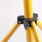 Zbliżenie na złącze statywu naświetlacza LED. Widoczne trzy żółte nogi statywu z czarnym mocowaniem. Elementy metalowe są wyraźnie widoczne, a statyw jest ustawiony w pozycji rozłożonej, gotowy do użycia.