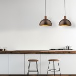 Brązowa lampa wisząca Oslo z oprawą w kształcie półkuli, zawieszona na cienkim przewodzie. Widoczna w nowoczesnej kuchni, nad drewnianym blatem i krzesłami barowymi. Wnętrze jasne, minimalistyczne.