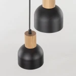 Cairo lampa wisząca z trzema oprawami E27, czarna z matowym wykończeniem. Posiada drewniane elementy w kolorze jasnego drewna. Ujęcie z góry, ukazujące dwa klosze w kształcie dzwonu, zawieszone na cienkim kablu. Tło jasne, neutralne.
