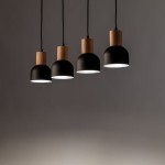 Cairo lampa wisząca z czterema kloszami, czarna, z drewnianymi elementami, zawieszona na czarnych przewodach. Klosze mają okrągły kształt i matowe wykończenie, emitują ciepłe światło. Ujęcie z przodu, na szarym tle.