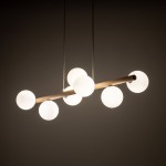 Lampa wisząca Estera z beżowym drewnem, zawieszona poziomo, z siedmioma okrągłymi kloszami z matowego szkła. Klosze rozmieszczone na drewnianej rurze, w jasnym, minimalistycznym stylu, na ciemnym tle.