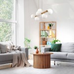 Lampa wisząca Estera w beżowym kolorze z 7 kulistymi kloszami w białym kolorze, zawieszona na drewnianym elemencie. Produkt w aranżacji nowoczesnego wnętrza, z szaro-beżową sofą i drewnianym stolikiem.