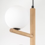Lampa wisząca Estera z trzema miejscami na żarówki G9, w kolorze beżowym z jasnym drewnem. Posiada okrągły, matowy klosz oraz prostą, drewnianą konstrukcję. Ujęcie z góry, ukazujące detale elementów mocujących i teksturę drewna.